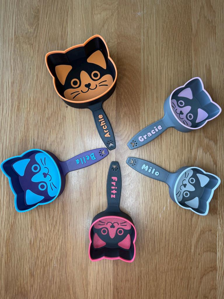 Cat-face shaped kibble scoop printed in two colors with a custom name