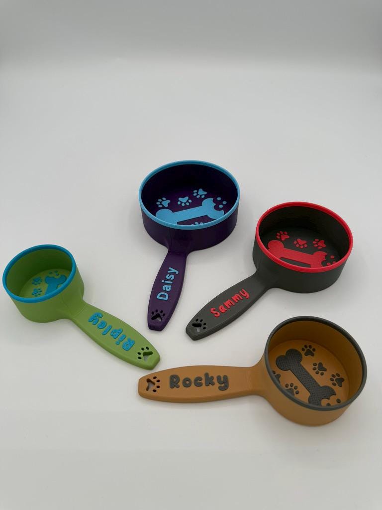 Personalized dog food scoops in green, navy and brown, each printed with a pet's name